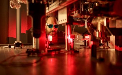 Male researcher under red light in a quantum physics lab.